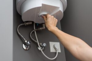 Woman hands setting temperature of water in heater electric boiler. Interior details close-up